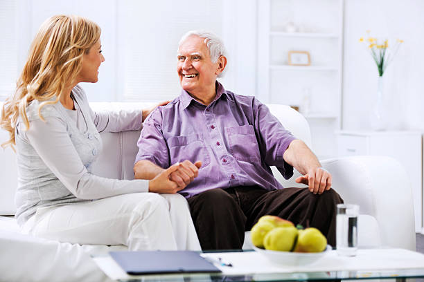 cuidador en el hogar de estar n el sofá con un anciano - senior living communitiy fotografías e imágenes de stock