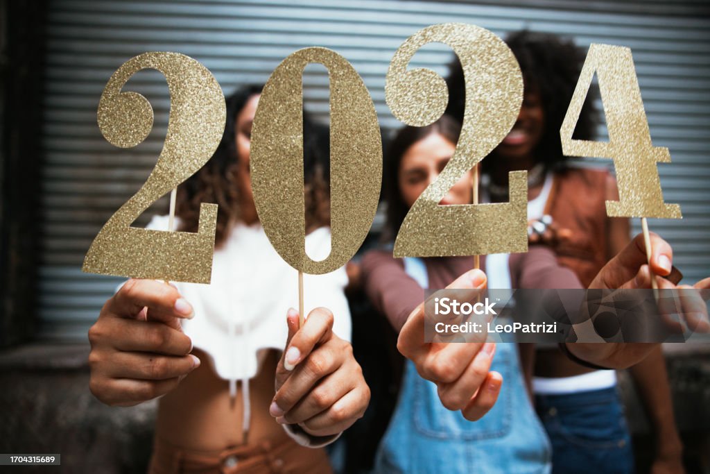 Group of friends celebrating 2024 new Year Group of friends holding the number 2024, celebration conceptual image for New Year’s Eve. New Year's Eve Stock Photo