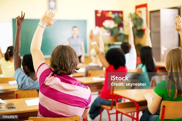 Group Of Teenagers Sitting In The Classroom With Raised Hands Stock Photo - Download Image Now
