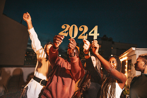 Group of friends holding the number 2024, celebration conceptual image for New Year’s Eve.