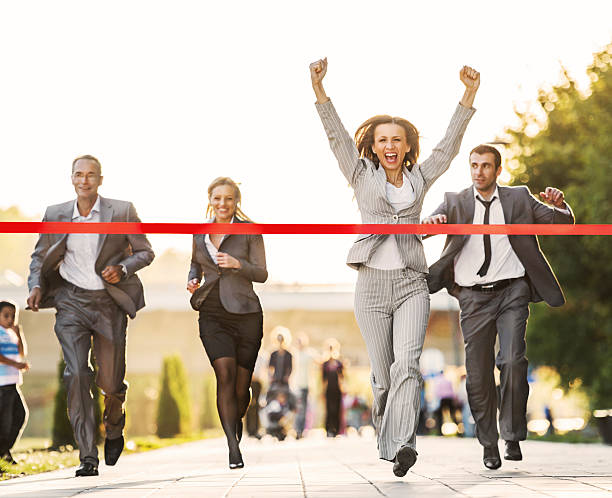 Business people running to finish, crossing red line. Happy businesswoman crossing finish line during race.    finish line photos stock pictures, royalty-free photos & images