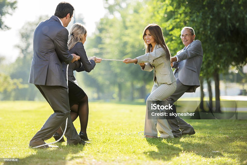 Businesspeople playing tug of war outdoors. Business workers in a tug-of-war pulling a rope.    Tug-of-war Stock Photo