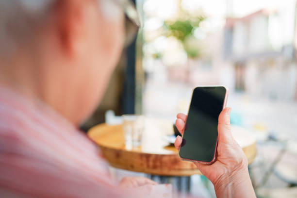 istock Senior Woman using mobile phone in coffee shop. 1704330412