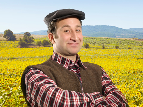 Happy farmer in front of a combine harvester in a sunflower field