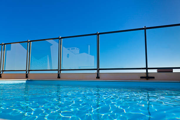 A rooftop pool with a glass rail on a sunny day stock photo