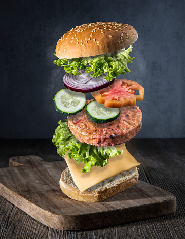 Maxi hamburger with flying ingredients placed on a table