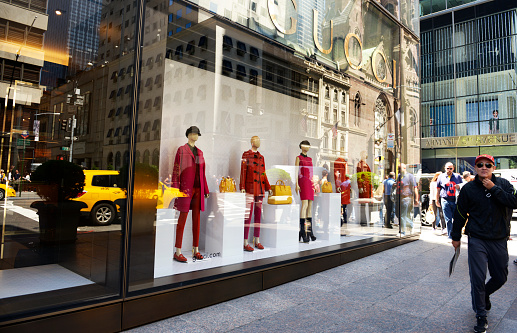New York City, USA - May 30rd 2014: One asian man walking in front of Gucci store.  Gucci is an Italian fashion and leather goods brand founded by Guccio Gucci in Florence in 1921.