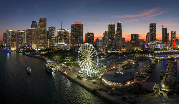 arranha-céus iluminados de brickell, o centro financeiro da cidade. skyviews miami observation wheel no bayside marketplace com reflexos na água da baía de biscayne e na paisagem urbana dos eua à noite - miami florida night florida skyline - fotografias e filmes do acervo