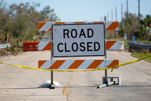 A diamond shaped road sign with traffic cones indicating the road is temporarily closed