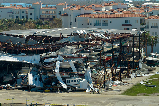 Warehouse with motorboats and yachts destroyed by hurricane winds in Florida coastal area. Natural disaster and its consequences.