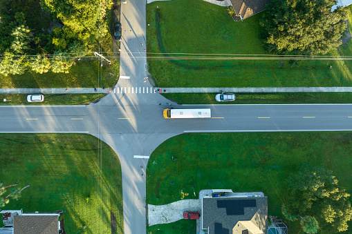 Top view of standard american yellow school bus picking up kids at rural town street stop for their lessongs in early morning. Public transport in the USA.