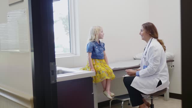 Little girl talks with female pediatrician during well visit