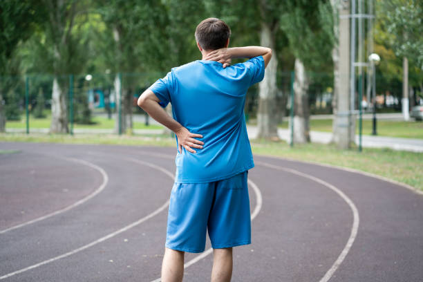 istock Back pain, athletic man with backache on a running track after workout 1704474519