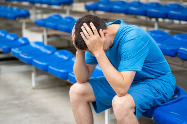 Headache and migraine, man with head pain after workout on a sports ground Headache and migraine, man with head pain after workout on a sports ground, health problems concept athlete fails stock pictures, royalty-free photos & images