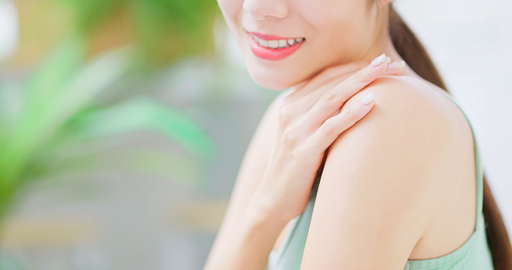 skin care concept - close up asian confident woman is smiling and touching her good skin on arms