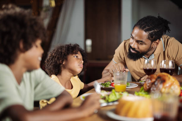 Young black father and daughter talking during a meal at dining table