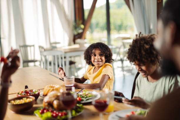 Smiling black  girl talking to her father during lunch at dining table