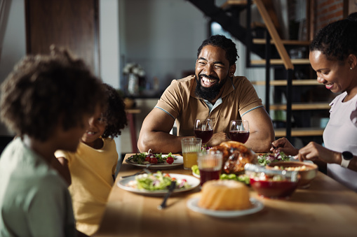 Happy African American  family talking during lunch time at dining table