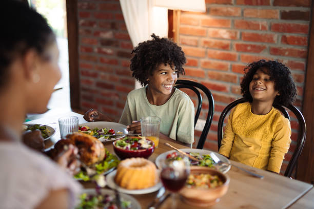 istock Happy black boy talking to his sister during lunch at dining table 1704521117