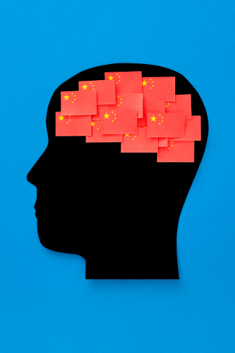 Paper collage of silhouette profile with china flags shaping the brain