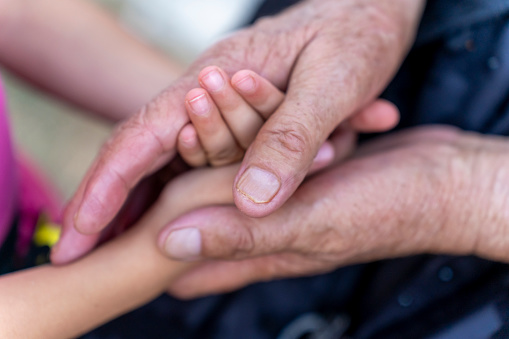 Asian Father touching and holding Little tiny Baby hand at outdoor together.