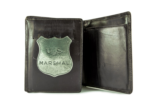 An old marshal badge in a wallet. White background.