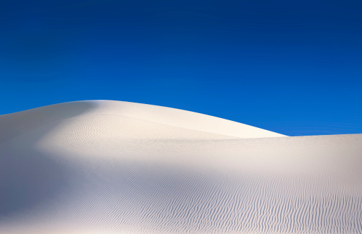 Clean landscape of white sand dunes against a clear blue sky