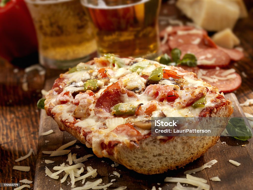 Deluxe French Bread Pizza Deluxe French Bread Pizza with Pepperoni,Mushrooms, Red and Green Peppers with Fresh Basil and Oregano and a Couple of Beers - Photographed on a Hasselblad H3D11-39 megapixel Camera System Baguette Stock Photo