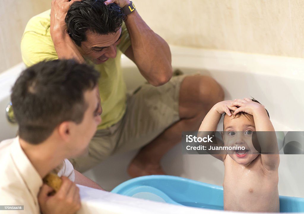 Child with two dads Two gay men couple playing with their child in the bathtub Child Stock Photo