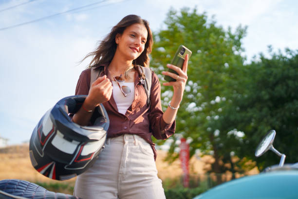 istock Young female driver using mobile phone next to her motorbike. 1704579892