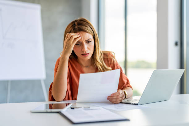 istock Sad and beautiful businesswoman doing some paperwork in a modern office. 1704585352