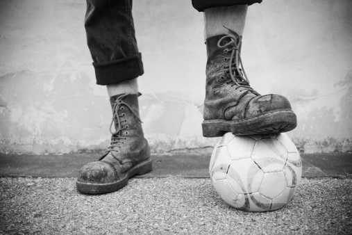 anti-racist skinhead wearing boots and showing his love for football (typical english hooligan). outdoor photo, daylight only. high contrast. selected focus on shoe laces.