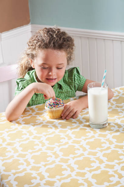 menina com um copo de leite comendo cupcake - sc0563 - fotografias e filmes do acervo