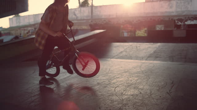 Sporty man making dangerous trick on bmx bike at skate park. Rider practicing.
