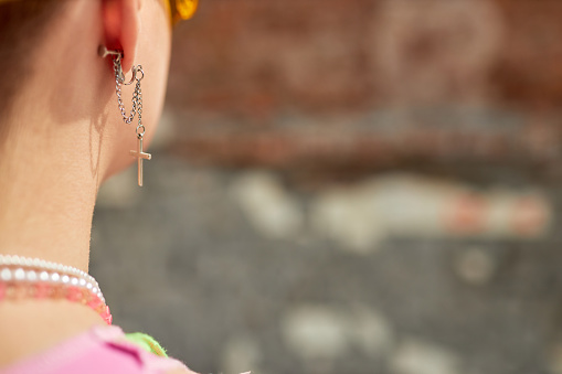 Closeup of unrecognizable girl in city with focus on chain earring, copy space