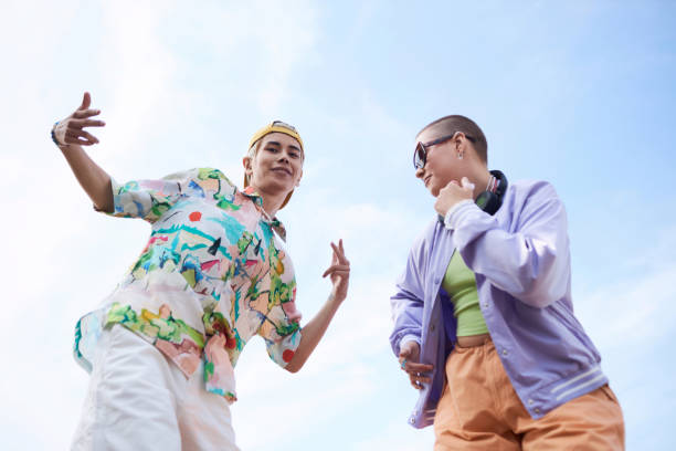 Minimal two young people dancing against clear blue sky and looking at camera