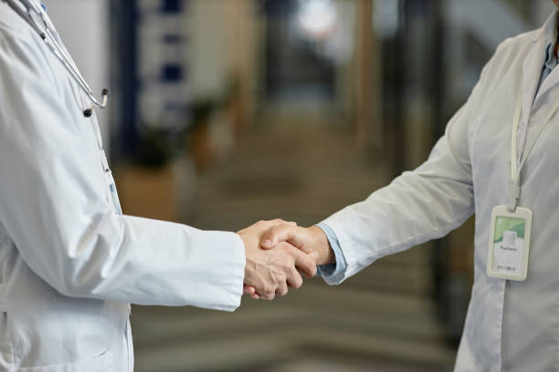 istock Close-up of hands of two general practitioners in lab coats during handshake 1704651175
