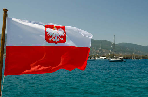 The state flag of Poland on the background of yachts at the anchorage.