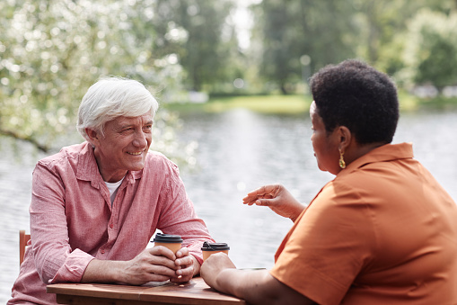 Portrait of multiethnic senior couple chatting cheerfully enjoying romantic date together at outdoor cafe