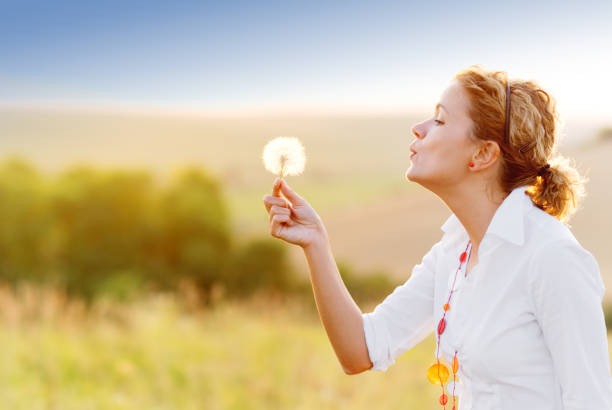 istock Young woman blowing a dandelion 170466367