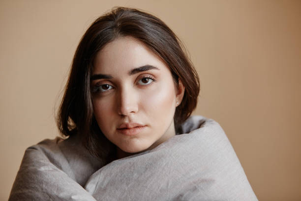istock Depressed young woman wrapped in blanket looking at camera 1704668983