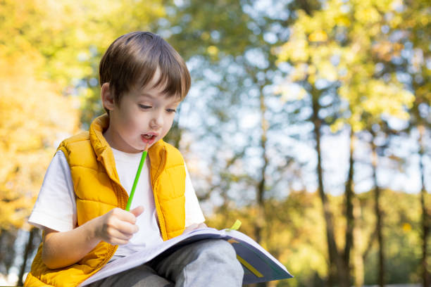 istock 6 year old boy in a public park doing homework 1704678287