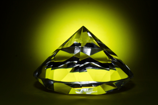 A piece of cut glass resembling a diamond backlighted yellow.