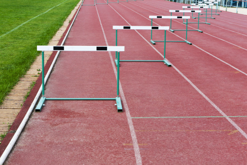 straight lanes of red cinder running track with barriers