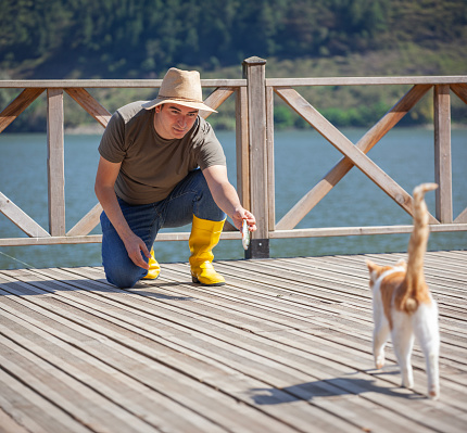 fisherman feeds the cat with fresh fish