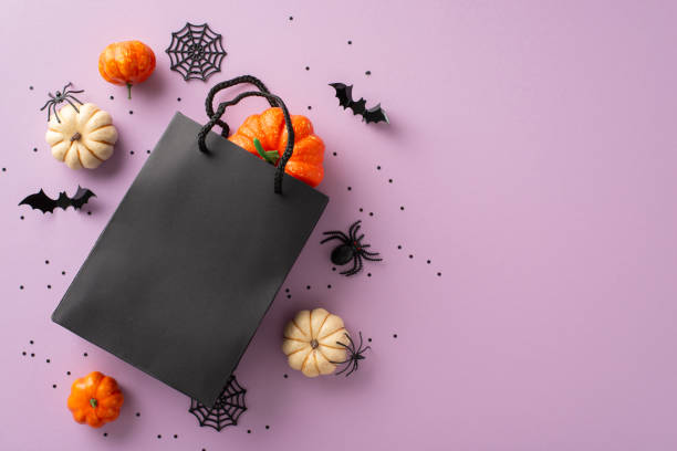 istock Generating Halloween joy with carefully selected presents. Captured from above, gift bag and festive decorations on violet isolated base, offering copyspace for promotional material or captions 1704730792