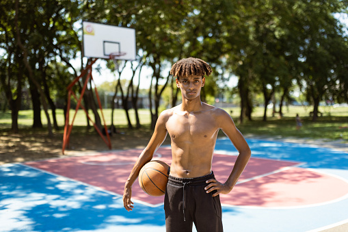 Young black basketball player on open basketball court, looking at the camera