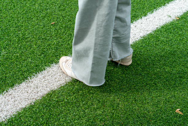 緑の人工芝サッカー場を歩く女の子の�足の接写 - soccer field grass single line lawn ストックフォトと画像