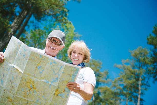 Senior Hikers Senior Hikers looking at map in the woods. couple hope sky blue stock pictures, royalty-free photos & images