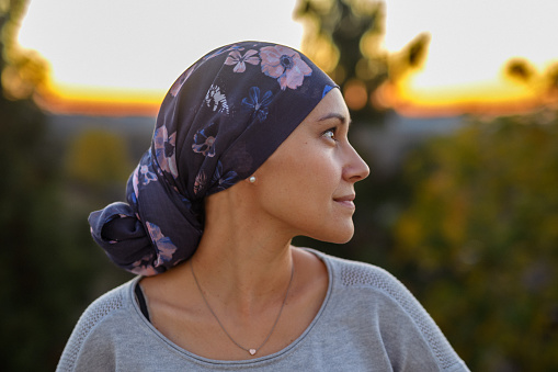 Portrait of a multiracial woman of Asian and Pacific Islander descent soaking in the beauty of nature while watching the sunset from the back patio of her home. The woman if filled with hope and gratitude for the support she has received from family, friends and her medical team.